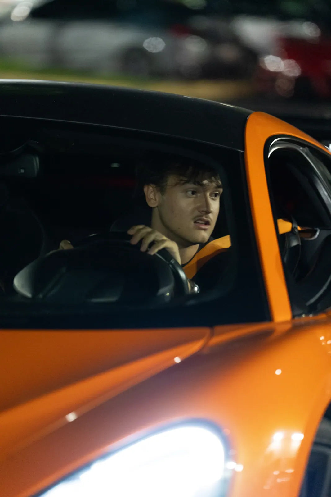 Driver at the wheel of an orange McLaren