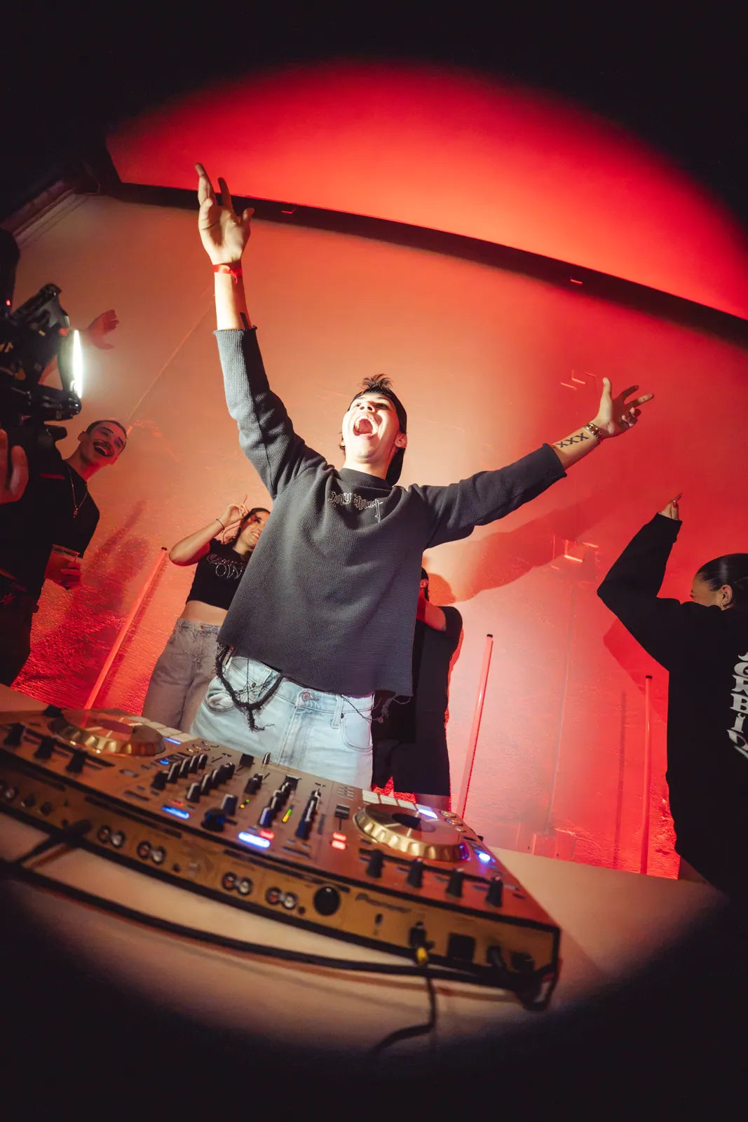 DJ with arms raised over the decks