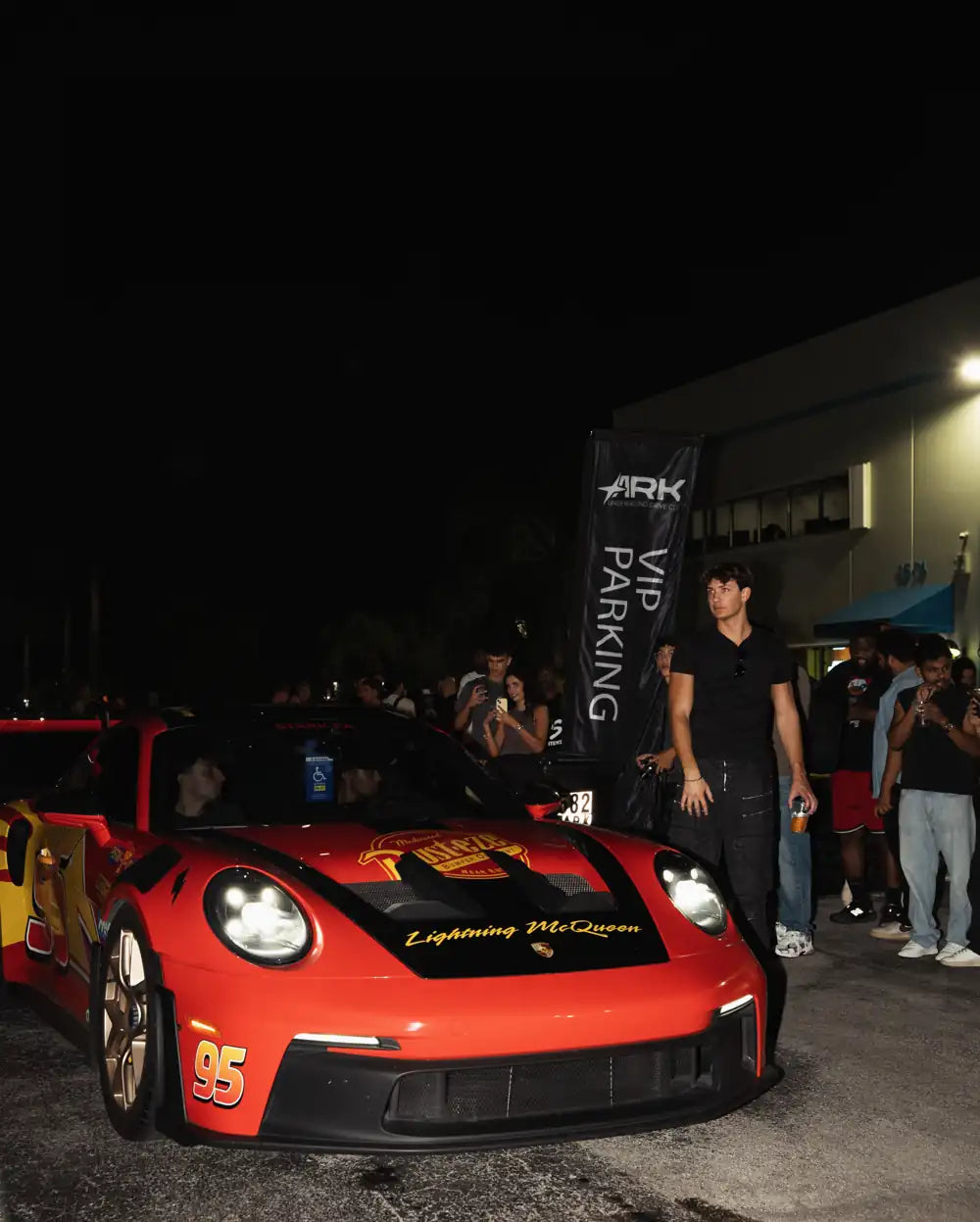 Red Porsche surrounded by guests outside Ark at night